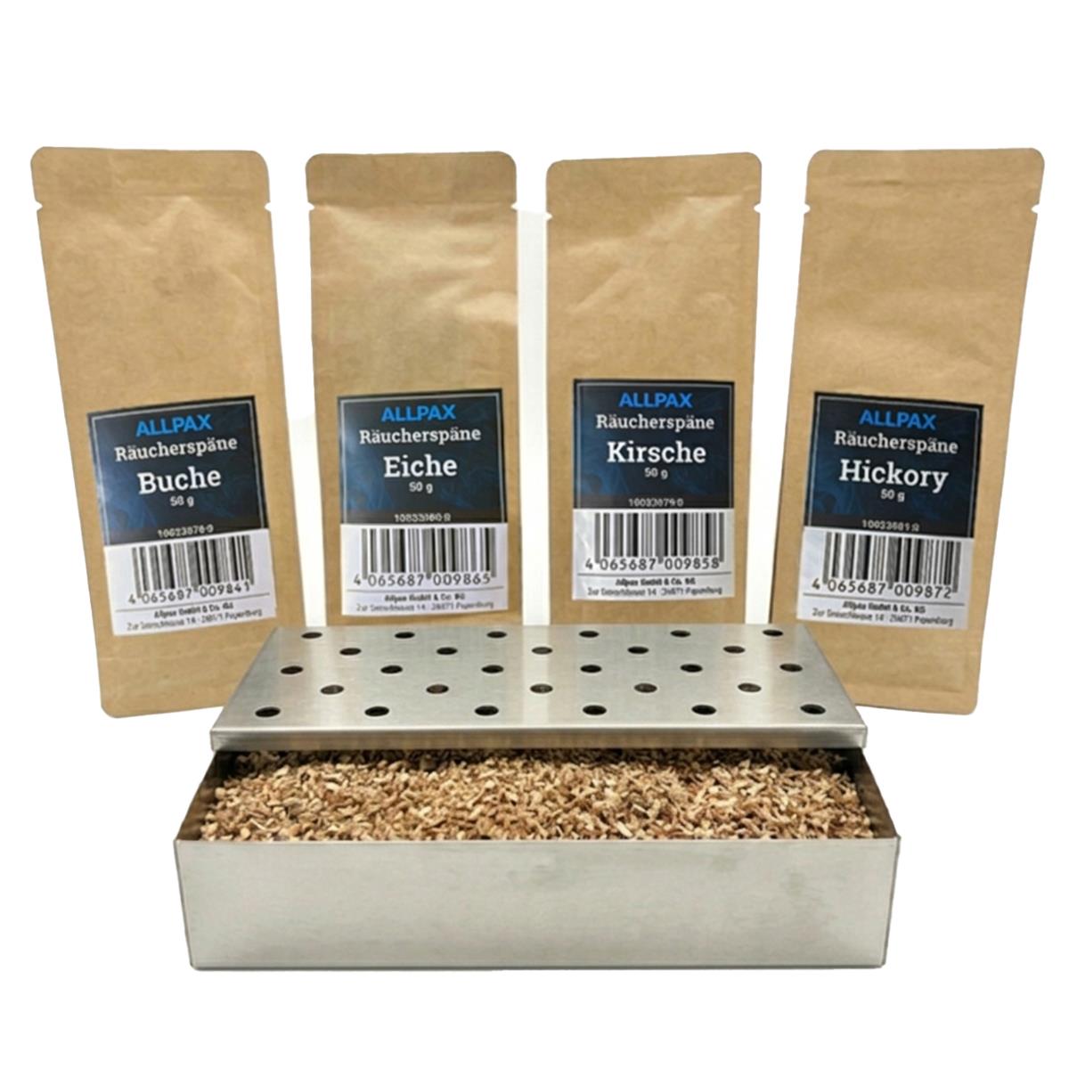 ALLPAX Räucherbox Smokerbox befüllt mit Räucherspänen, im Hintergrund Räucherspänepackungen Buche, Eiche, Kirsche und Hickory