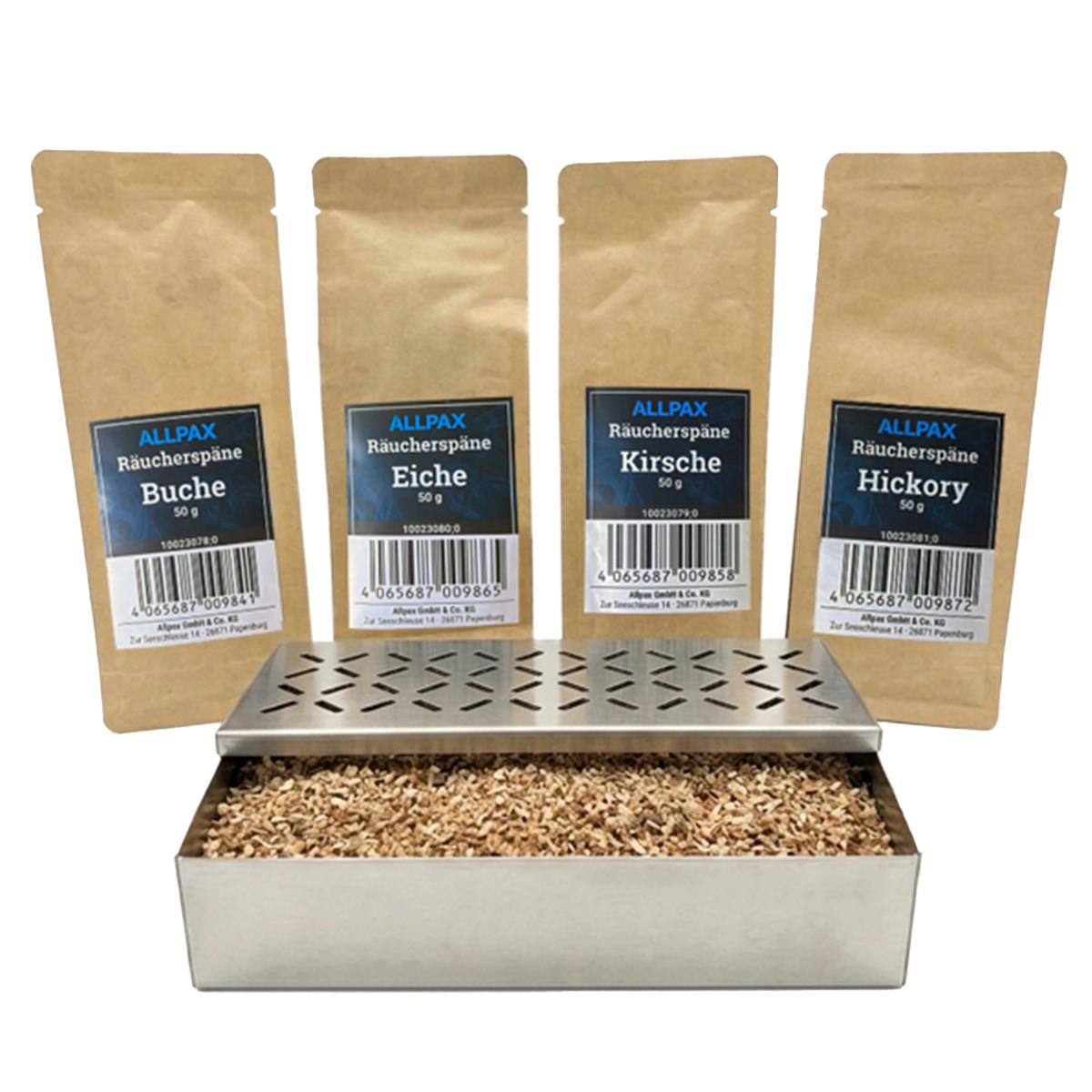 ALLPAX Räucherbox Smokerbox befüllt mit Räucherspänen, im Hintergrund Räucherspänepackungen Buche, Eiche, Kirsche und Hickory