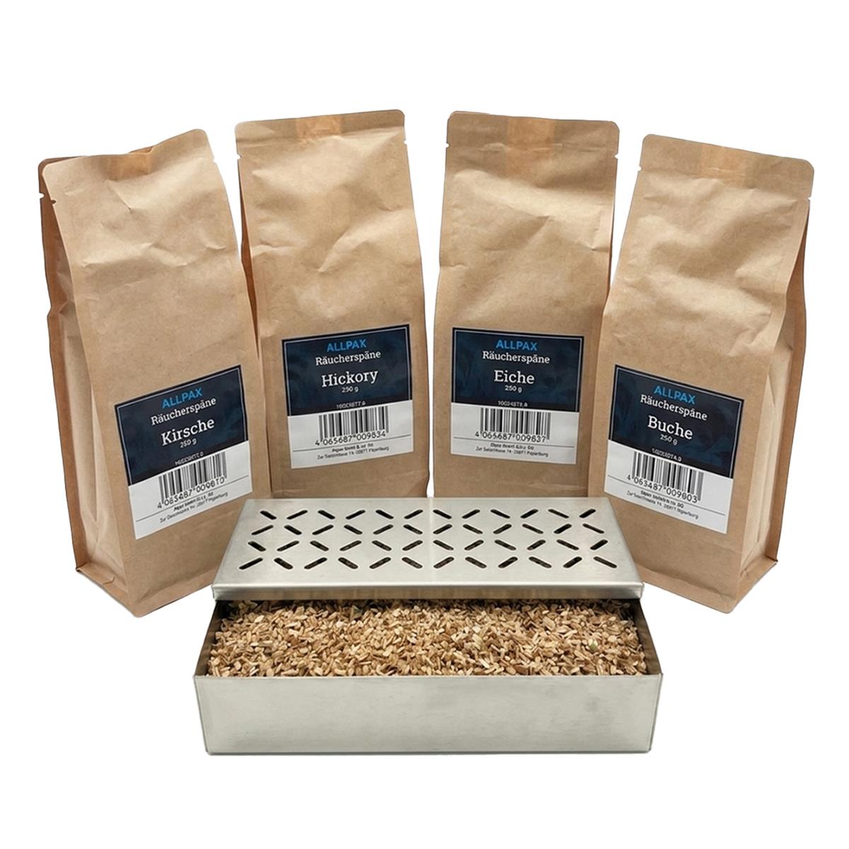 ALLPAX Räucherbox Smokerbox befüllt mit Räucherspänen, im Hintergrund Räucherspänepackungen Buche, Eiche, Kirsche und Hickory