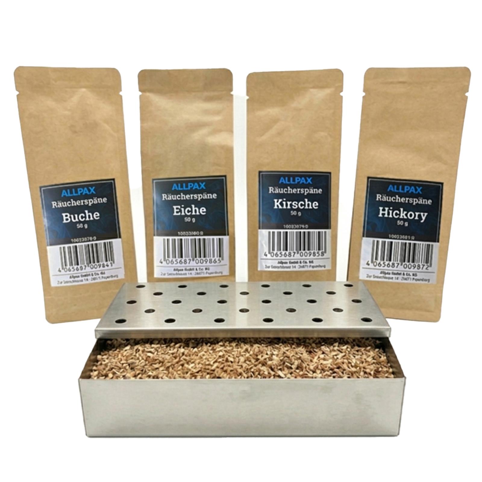 ALLPAX Räucherbox Smokerbox befüllt mit Räucherspänen, im Hintergrund Räucherspänepackungen Buche, Eiche, Kirsche und Hickory