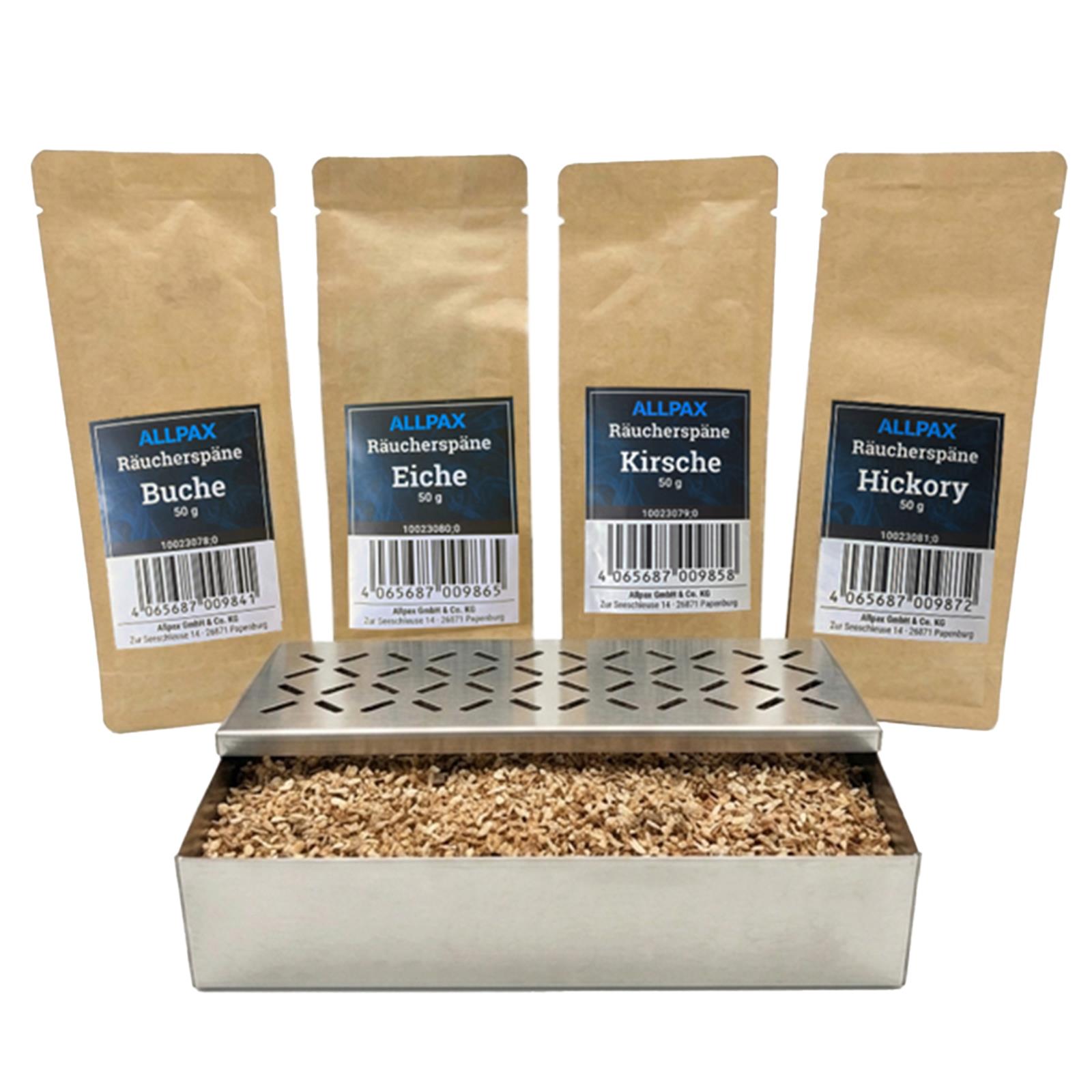 ALLPAX Räucherbox Smokerbox befüllt mit Räucherspänen, im Hintergrund Räucherspänepackungen Buche, Eiche, Kirsche und Hickory